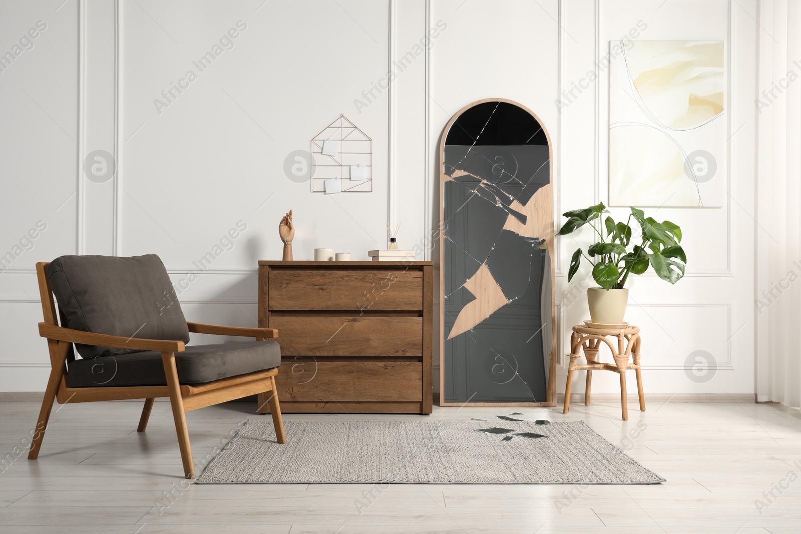 Photo of Broken mirror, wooden chest of drawers, armchair and houseplant in room