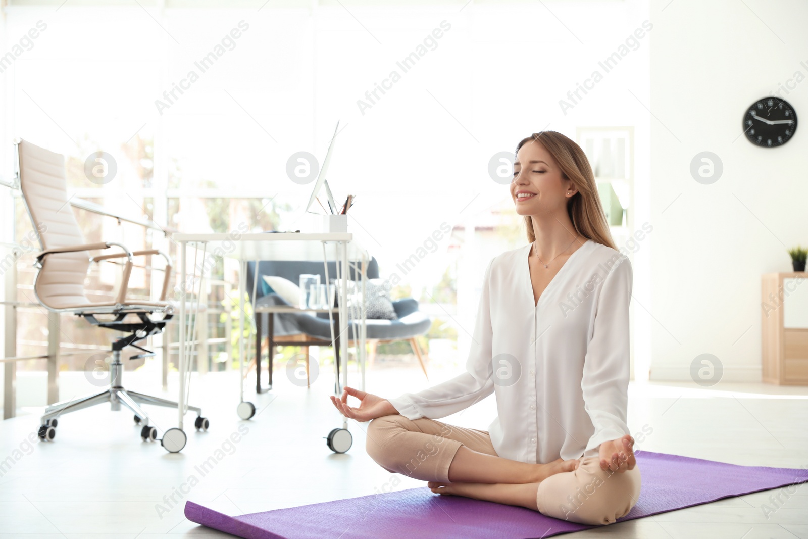 Photo of Young businessman doing yoga exercises in office. Workplace fitness