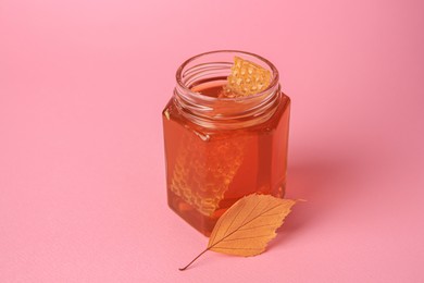 Photo of Jar with honey and autumn leaf on pink background