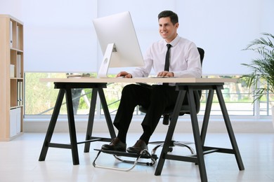 Photo of Man using footrest while working on computer in office