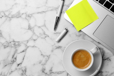 Laptop with blank sticky note, pen and cup of coffee  on white marble table, flat lay. Space for text