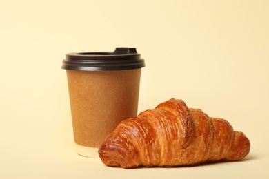 Paper coffee cup and croissant on color background. Mockup for design