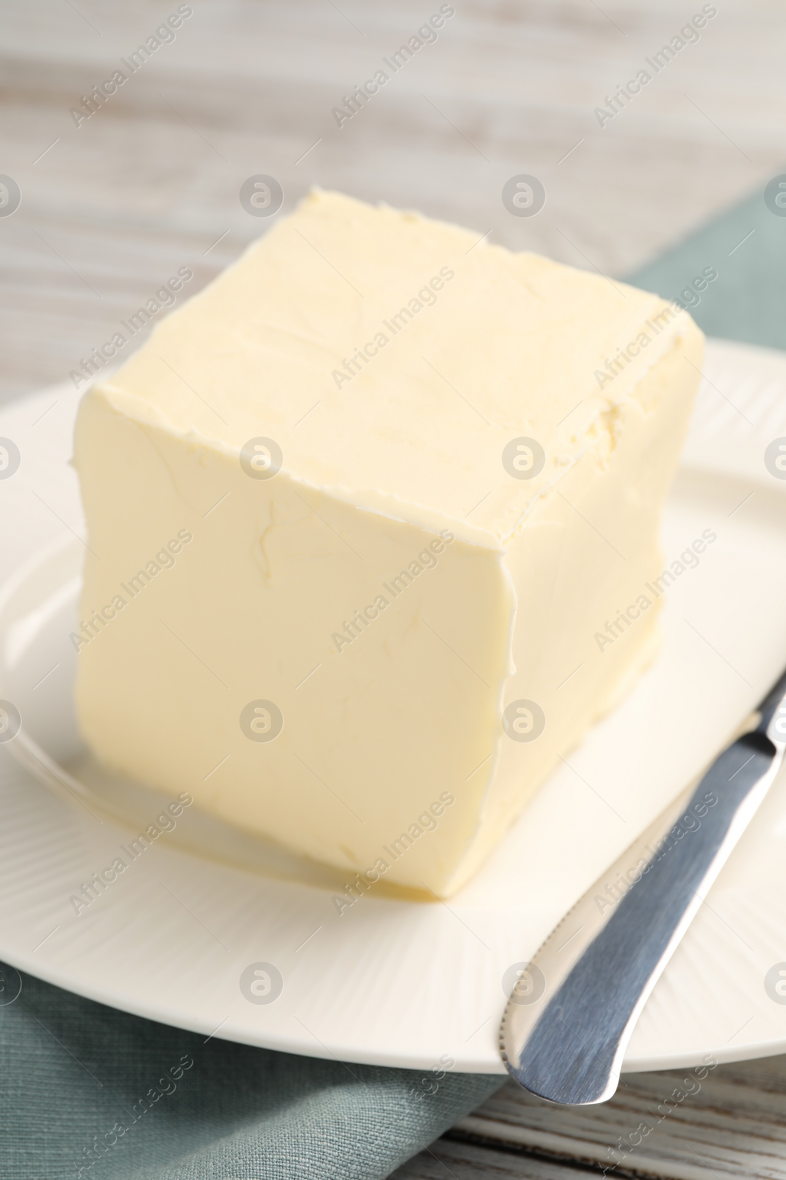 Photo of Block of tasty butter and knife on white wooden table, closeup