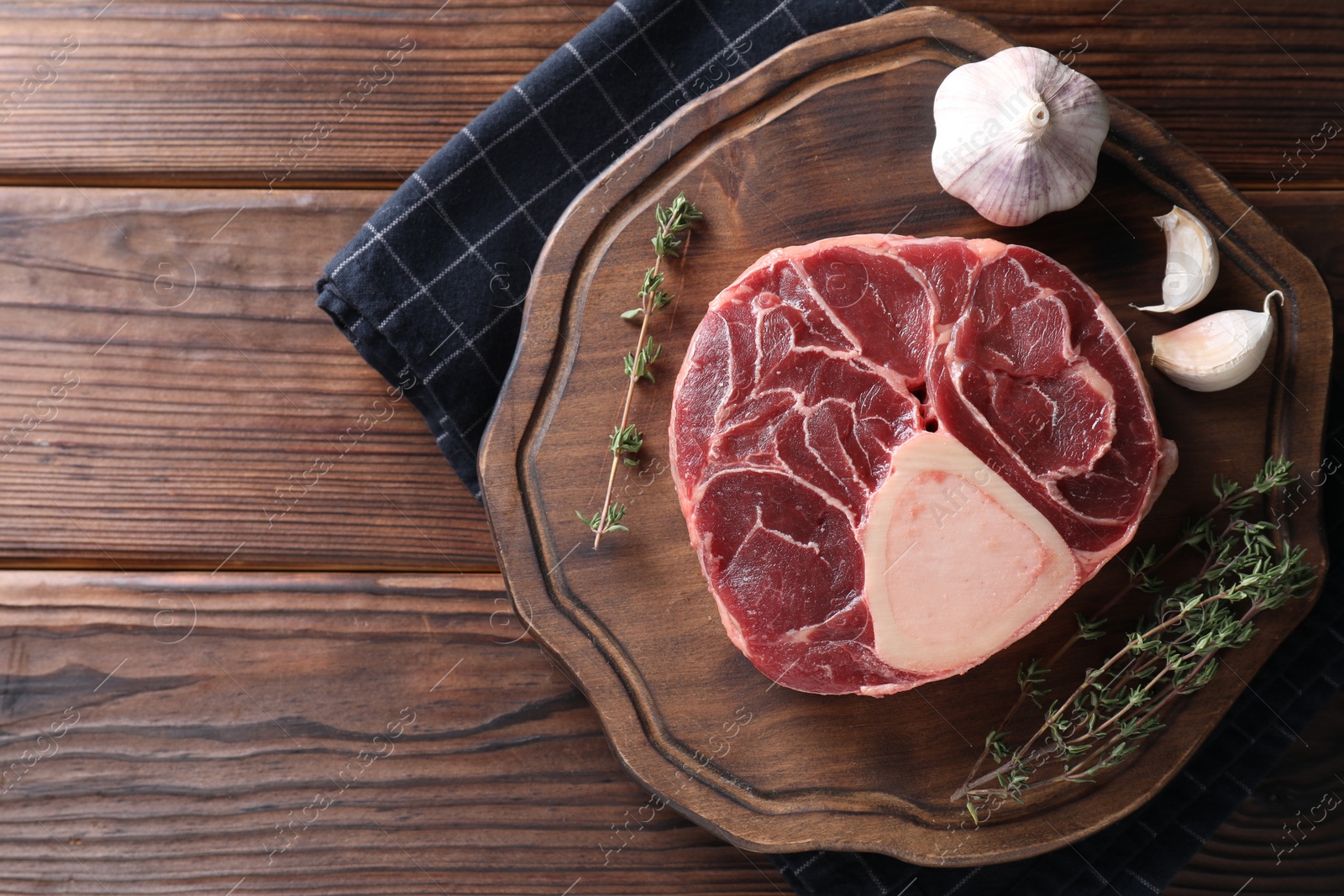 Photo of Piece of raw beef meat, thyme and garlic on wooden table, top view. Space for text