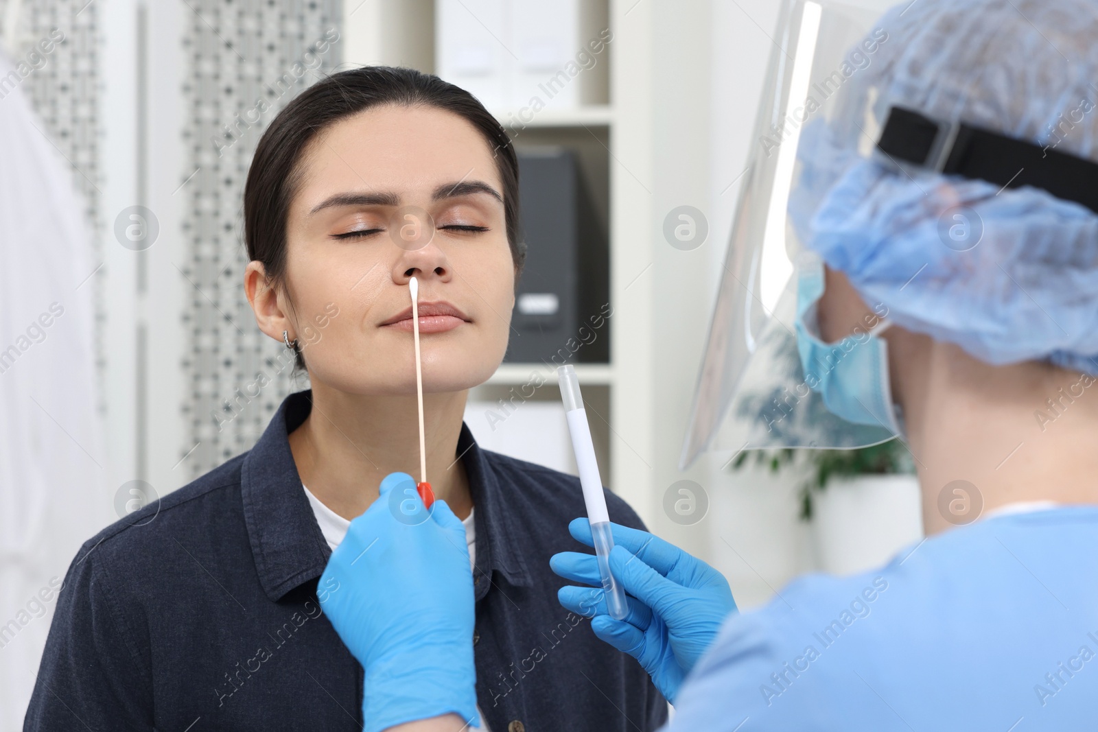 Photo of Laboratory testing. Doctor in uniform taking sample from patient's nose with cotton swab at hospital