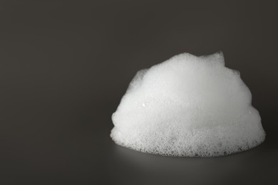 Photo of Drop of fluffy bath foam on grey background, closeup. Space for text