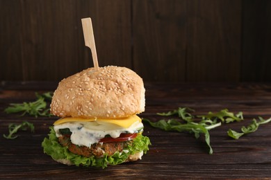 Delicious vegetarian burger and arugula on wooden table