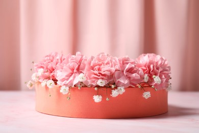 Photo of Orange round stand, gypsophila and carnation flowers on pink marble table, closeup. Stylish presentation for product