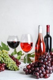 Photo of Fresh ripe juicy grapes and wine on white wooden table