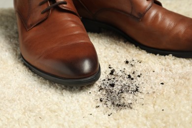 Photo of Brown shoes and mud on beige carpet, closeup