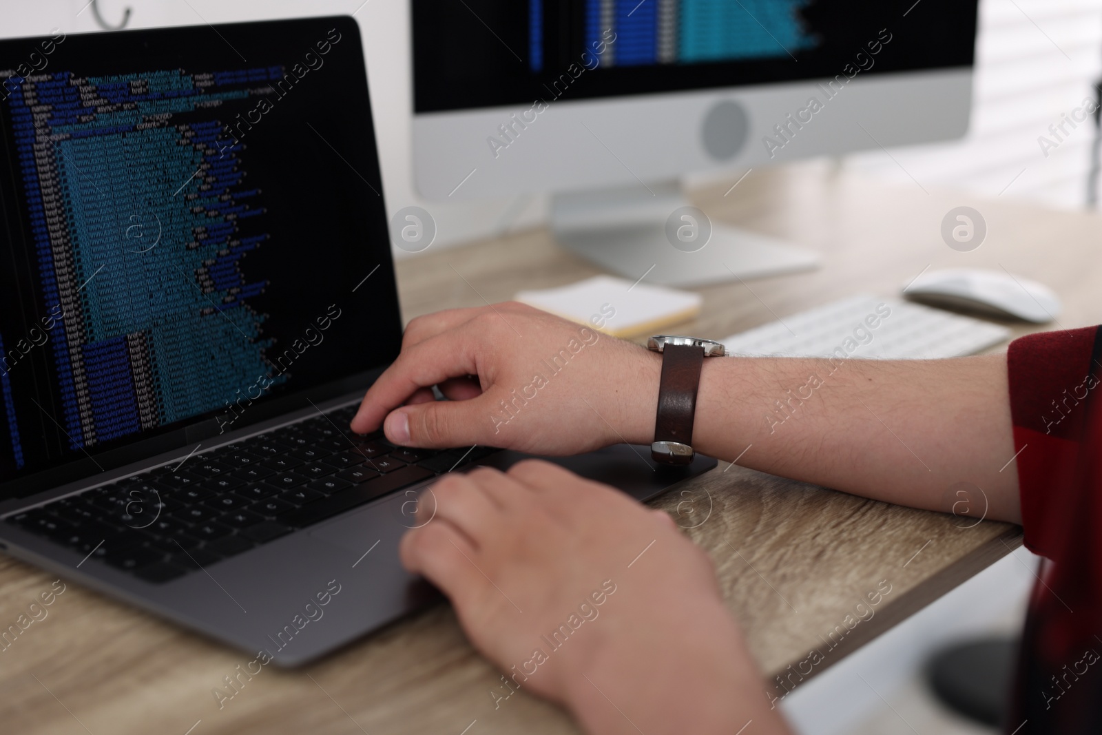 Photo of Programmer working with laptop at desk in office, closeup