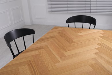 Photo of Wooden table and black chairs in room. Interior design