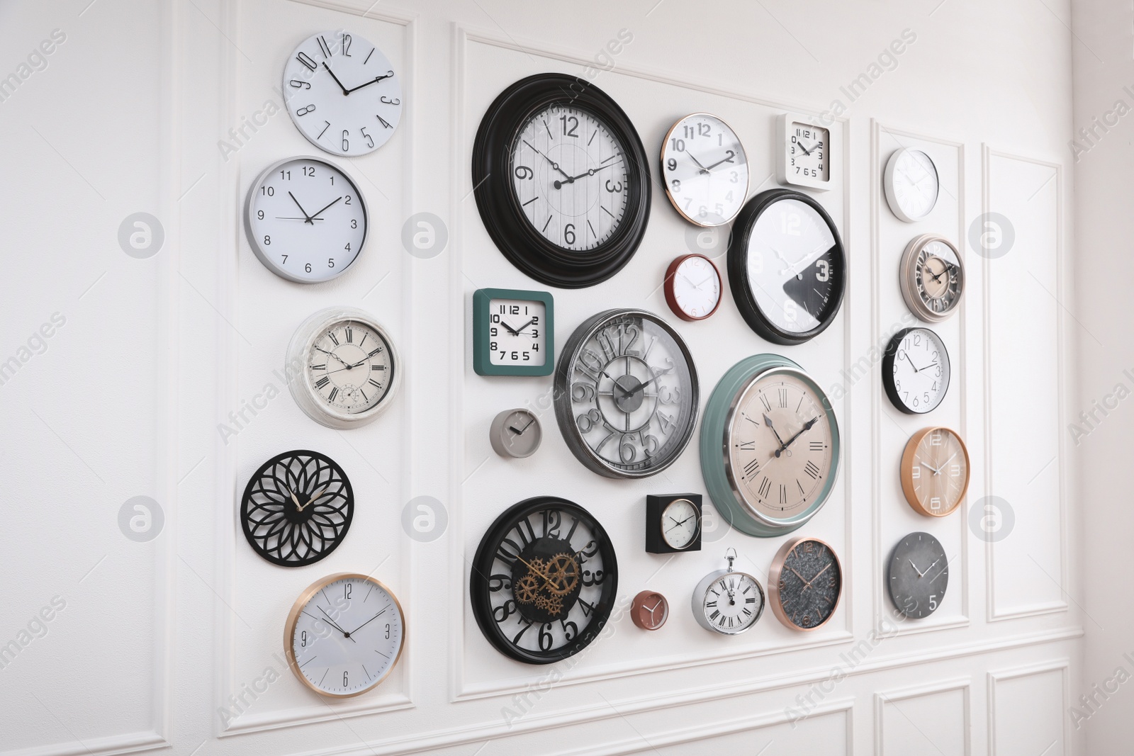 Photo of Collection of different clocks hanging on white wall