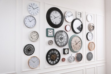 Collection of different clocks hanging on white wall