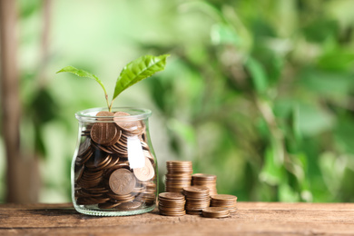 Photo of Money and sprout on wooden table against green blurred background, space for text
