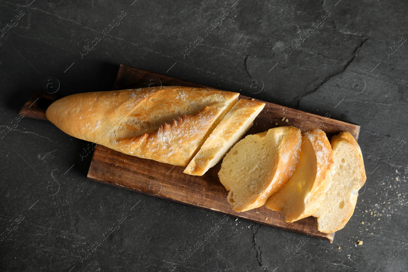 Photo of Board with bread on dark background, top view