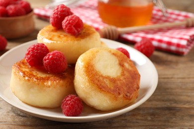 Delicious cottage cheese pancakes with raspberries on wooden table, closeup