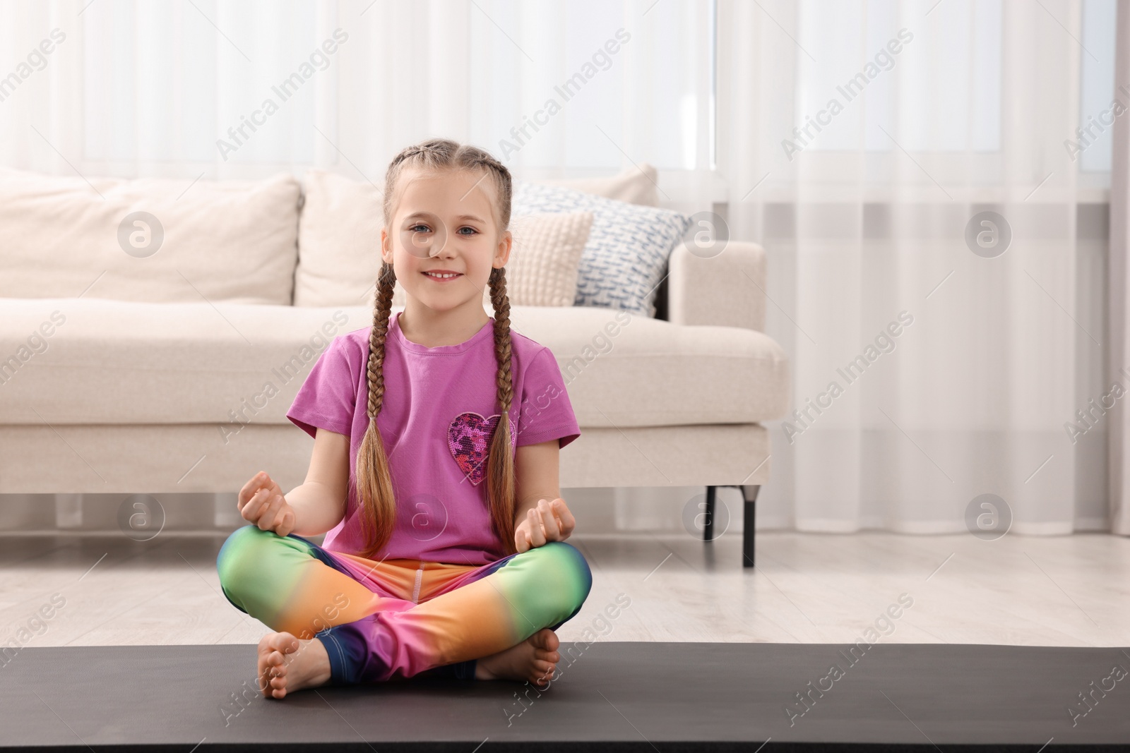 Photo of Little girl meditating at home, space for text. Harmony and zen