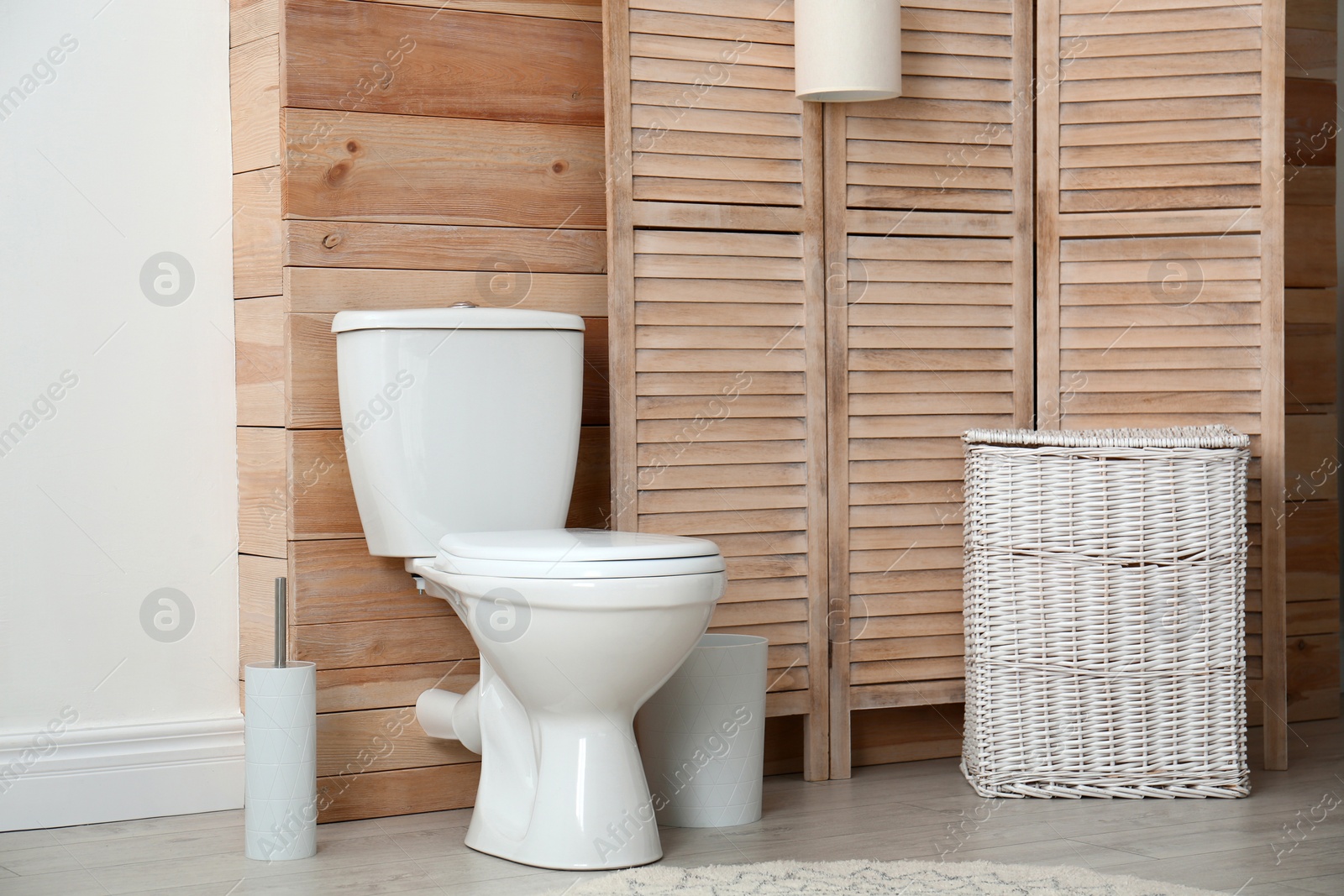 Photo of Toilet bowl near wooden wall in modern bathroom interior