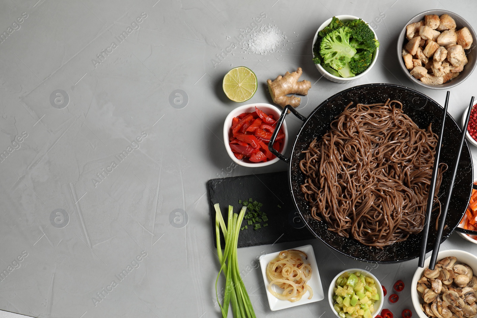 Photo of Wok with noodles, chicken and other products on light grey table, flat lay. Space for text