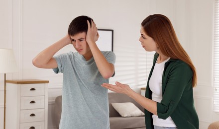 Photo of Mother scolding his son at home. Teenager problems