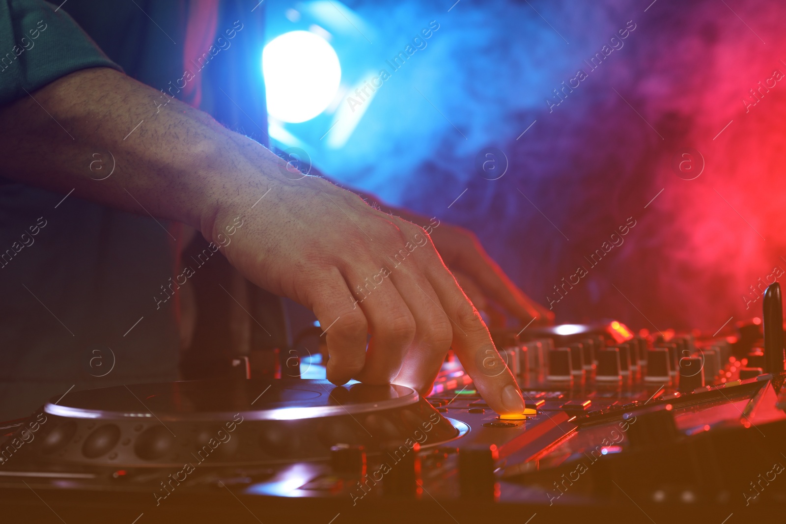 Photo of DJ creating music on modern console mixer in night club, closeup