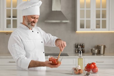 Photo of Professional chef making delicious tomato sauce at white marble table indoors. Space for text