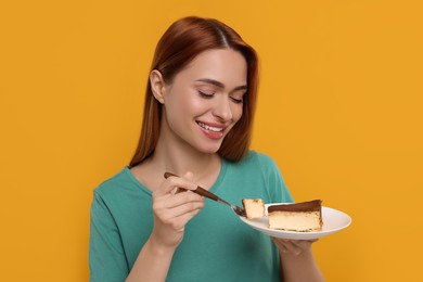 Young woman eating piece of tasty cake on orange background