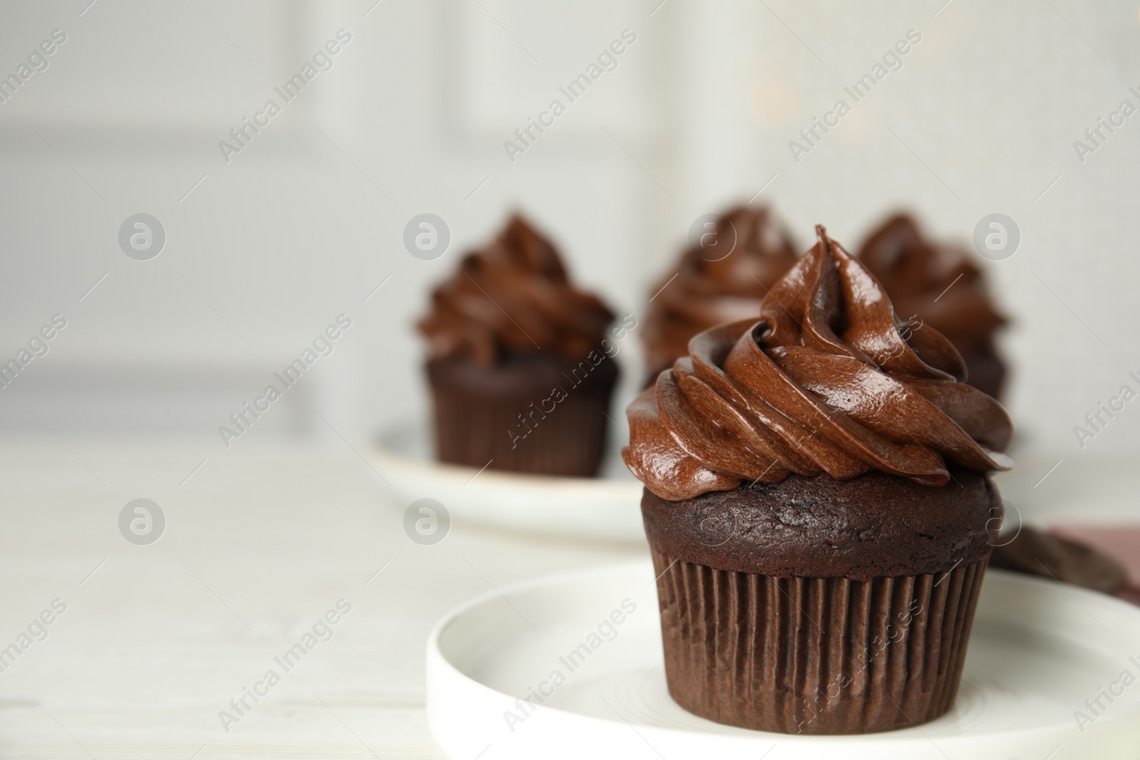 Photo of Plate with delicious chocolate cupcake on white table. Space for text