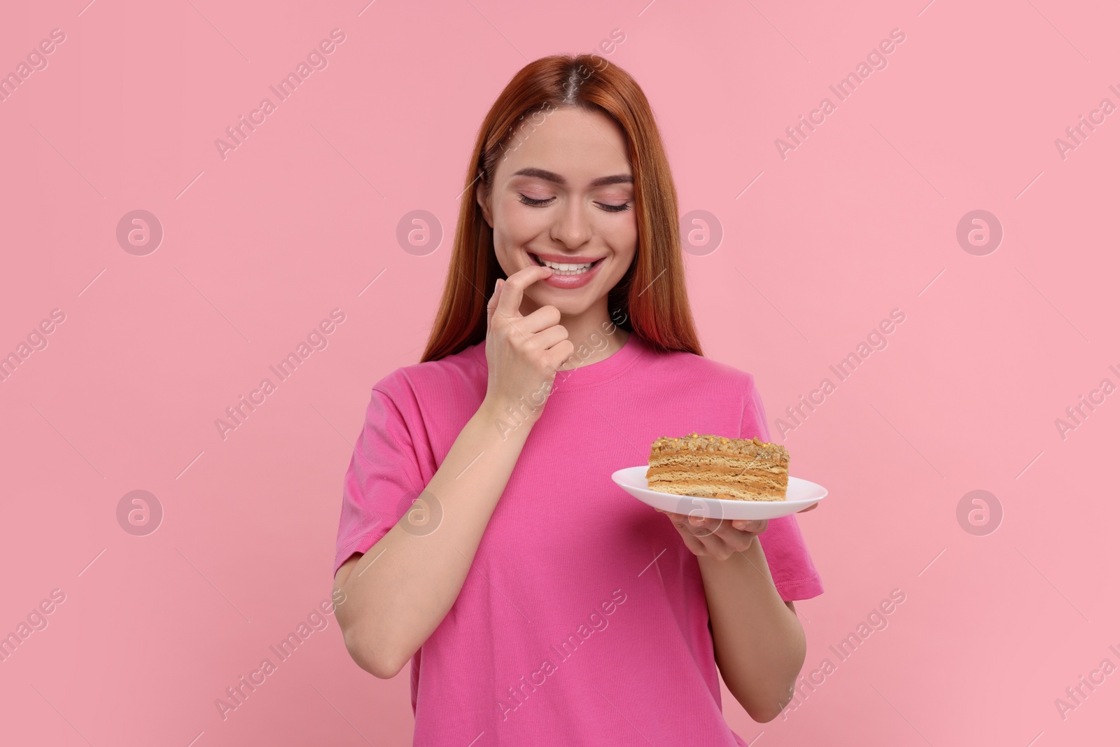 Photo of Young woman with piece of tasty cake on pink background