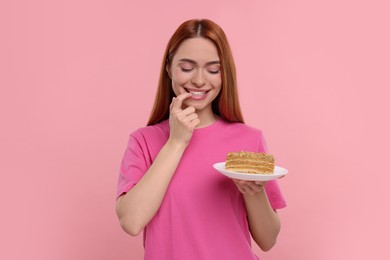 Photo of Young woman with piece of tasty cake on pink background