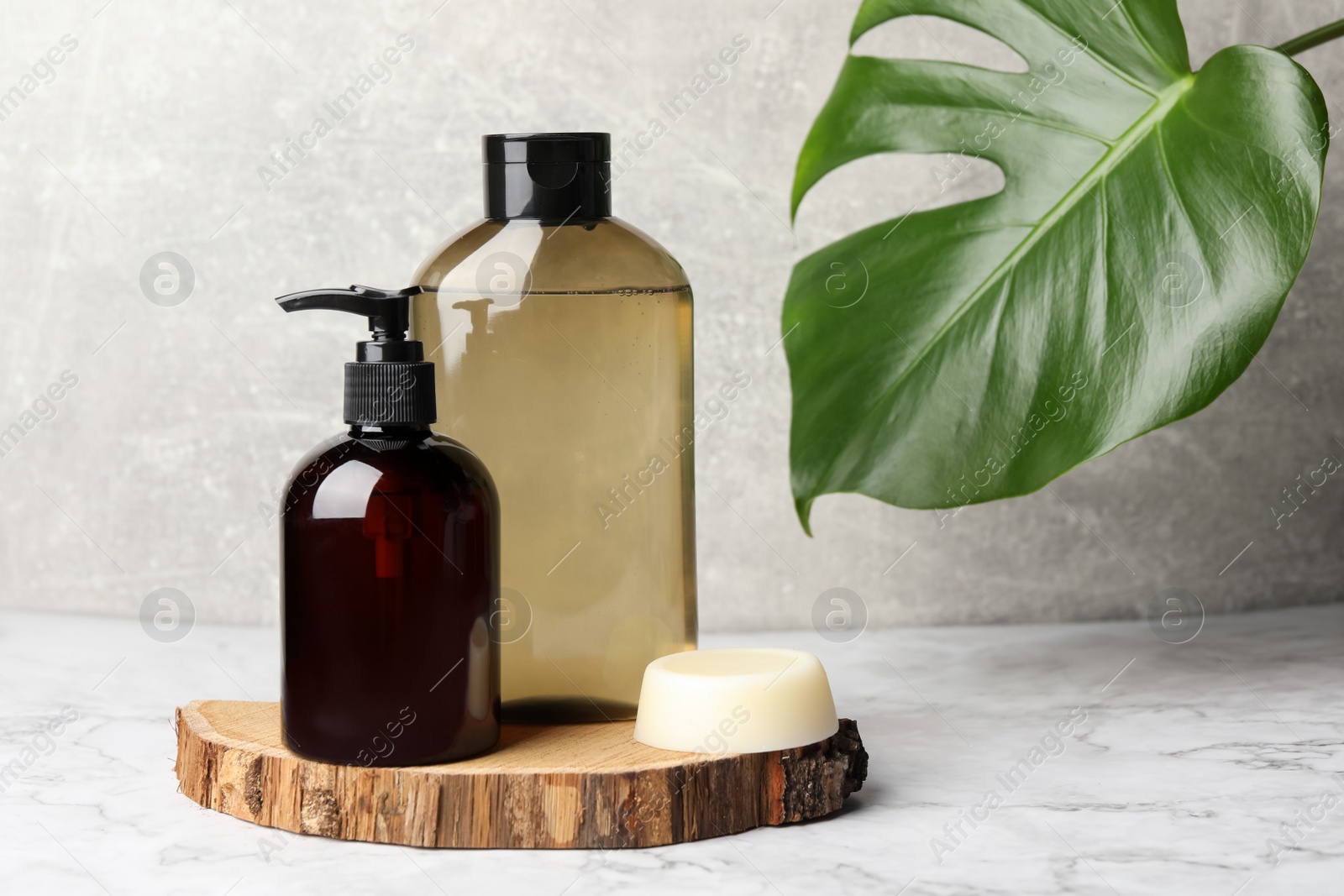 Photo of Solid shampoo bar and bottles of cosmetic product on white marble table, space for text