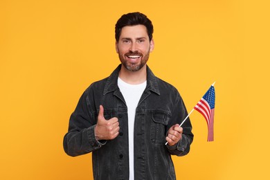 Photo of 4th of July - Independence Day of USA. Happy man with American flag showing thumbs up on yellow background
