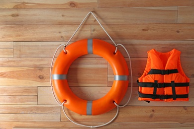 Orange life jacket and lifebuoy on  wooden background. Rescue equipment