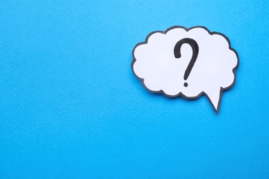 Photo of Paper speech bubble with question mark on light blue background, top view. Space for text