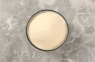 Photo of Uncooked organic semolina in bowl on grey table, top view