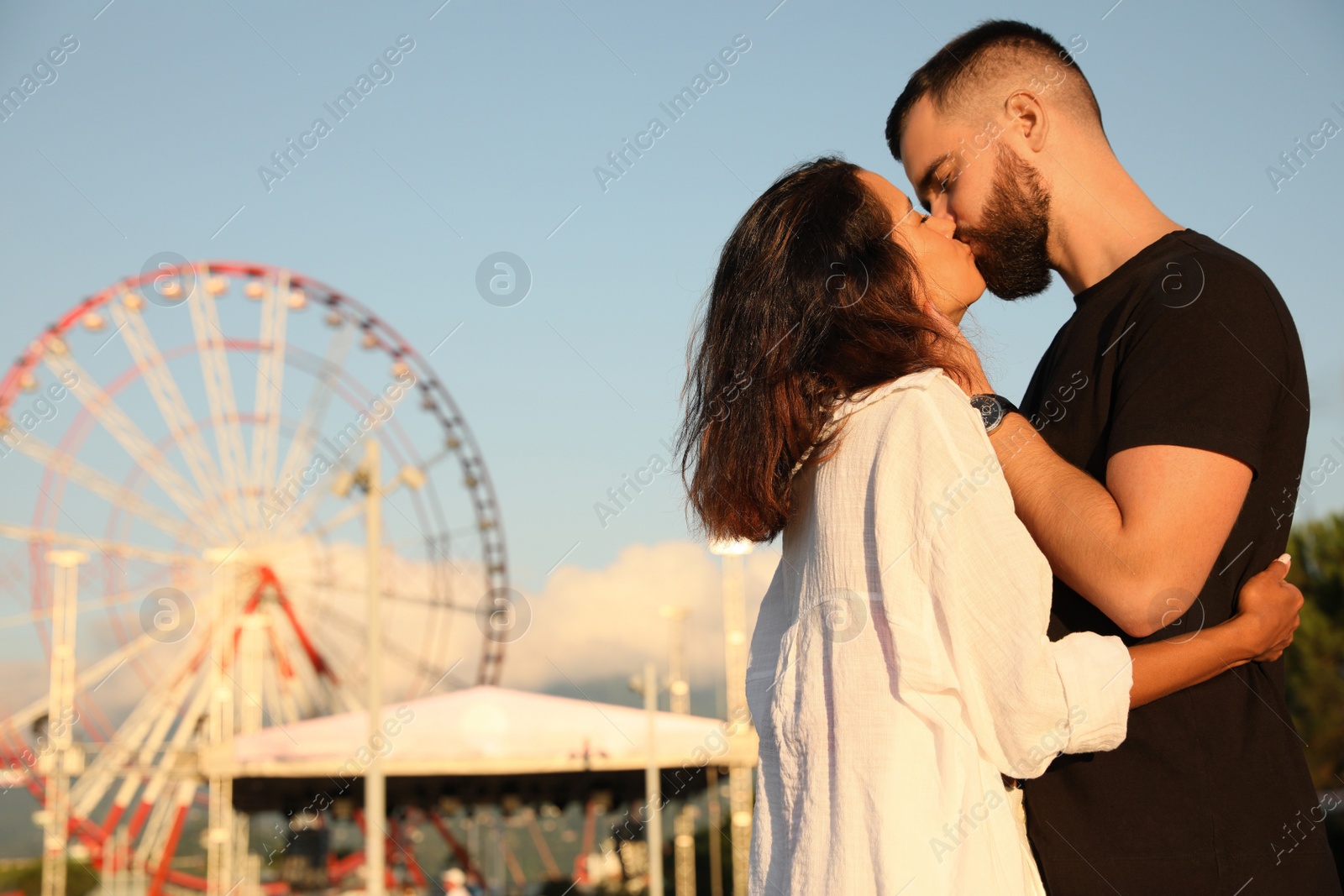 Photo of Happy young couple kissing in amusement park