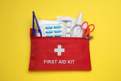 Photo of First aid kit on yellow background, top view