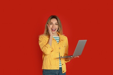 Photo of Young woman with modern laptop on red background