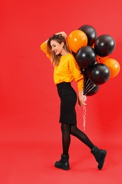 Beautiful woman with balloons on red background. Halloween party