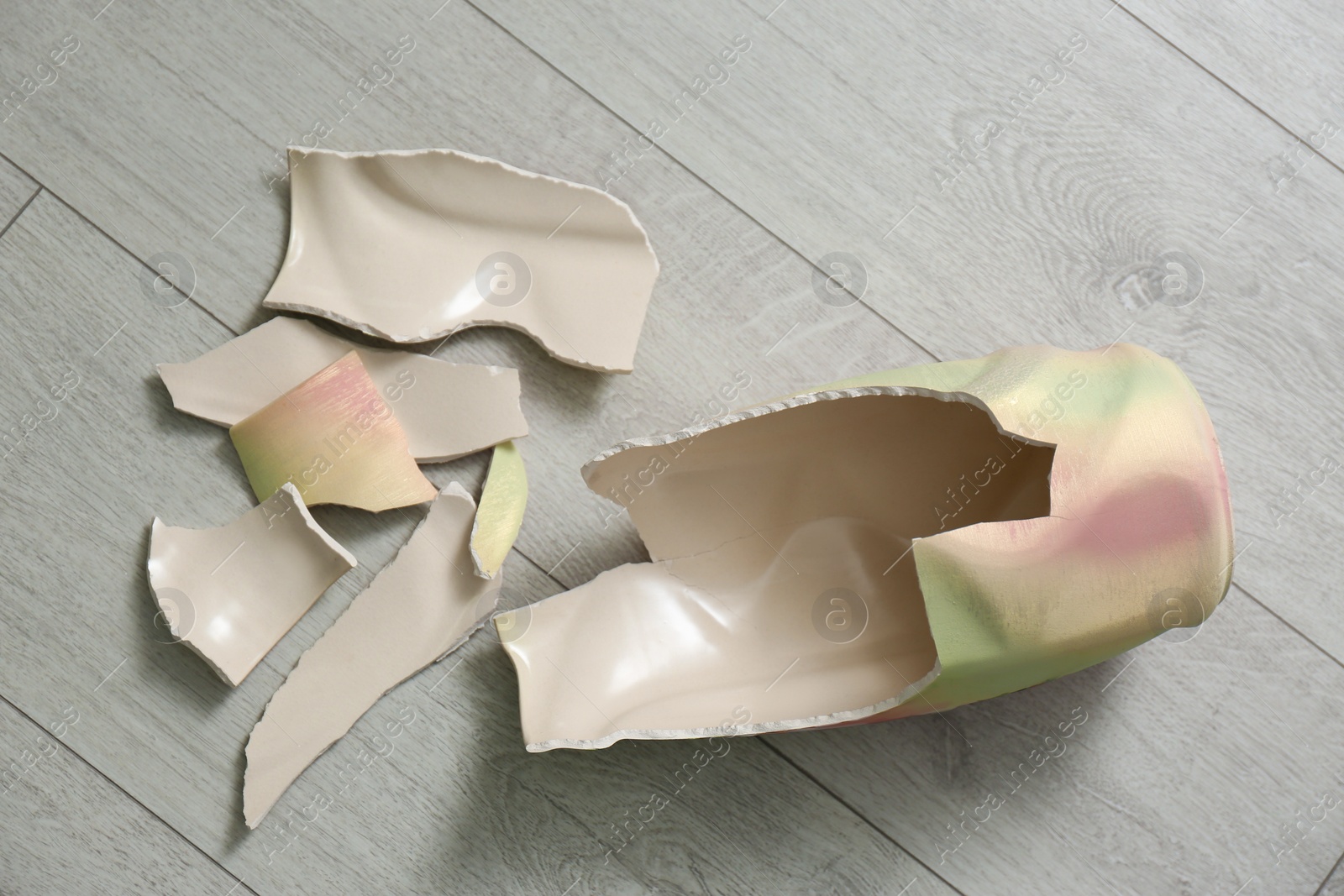 Photo of Broken ceramic vase on wooden floor, flat lay