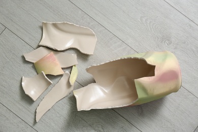 Broken ceramic vase on wooden floor, flat lay