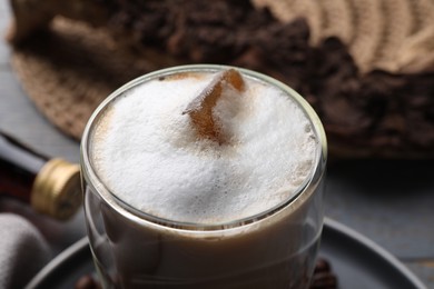 Glass of coffee with delicious syrup on table, closeup view