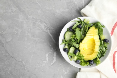 Delicious avocado salad with blueberries in bowl on grey marble table, flat lay. Space for text