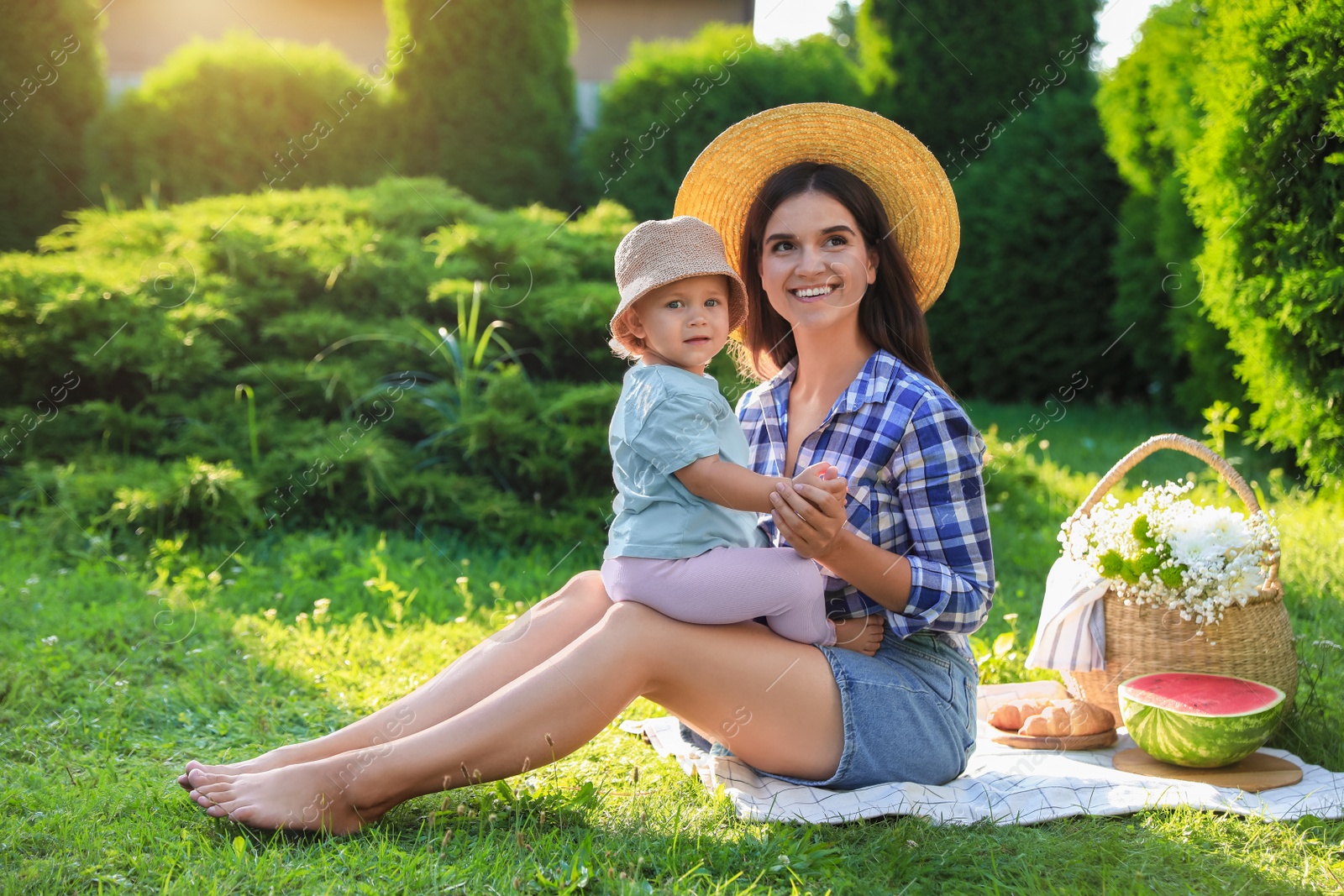 Photo of Mother with her baby daughter having picnic in garden on sunny day