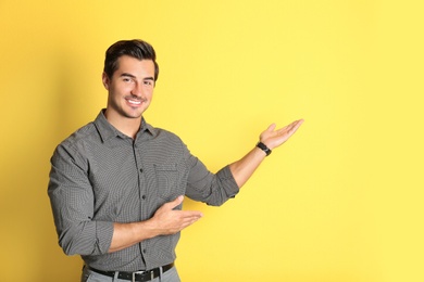 Young male teacher on yellow background. Space for text