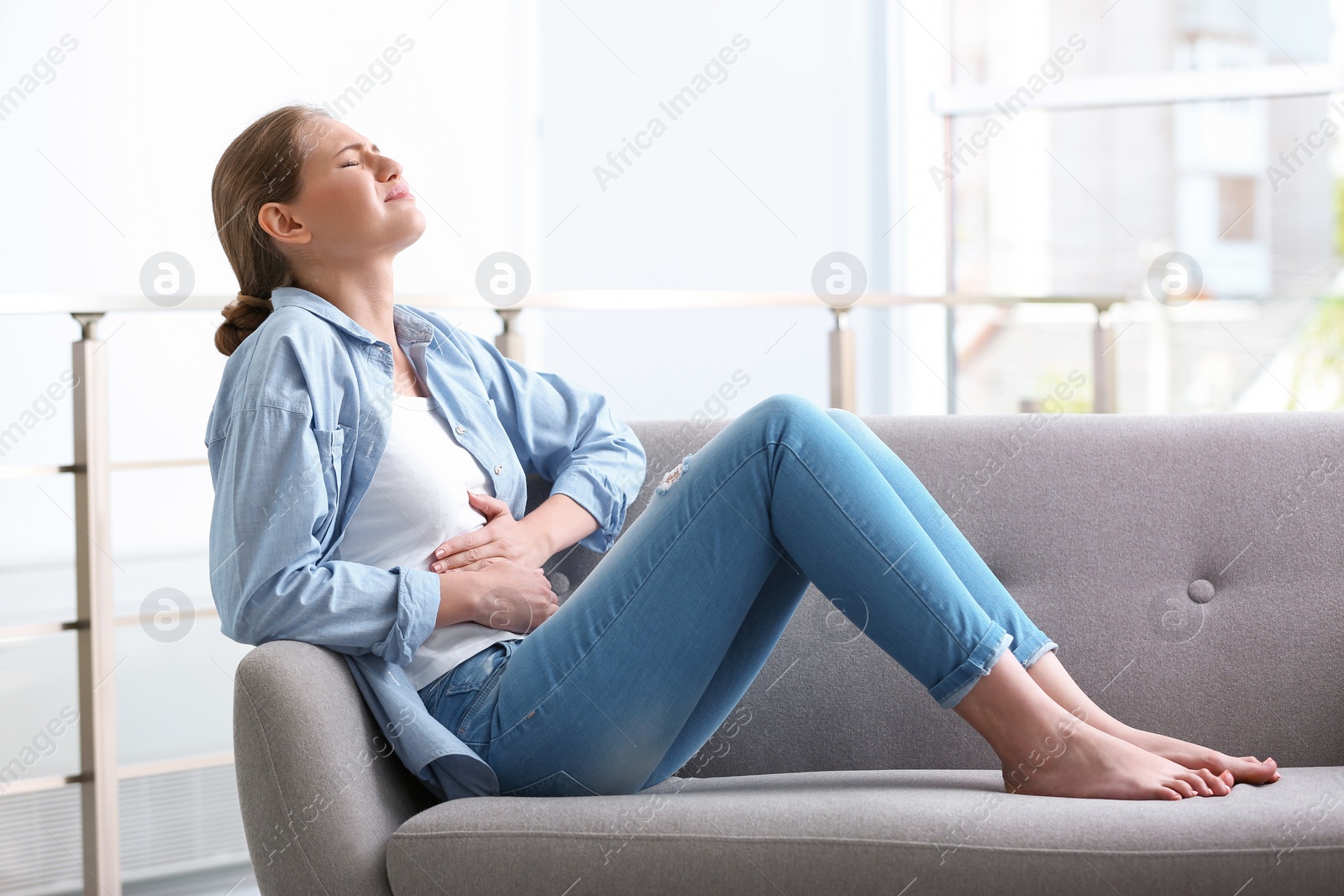 Photo of Young woman suffering from menstrual cramps at home. Gynecology