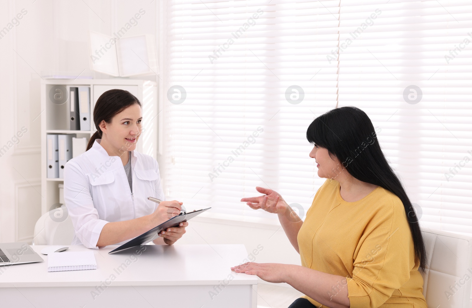 Photo of Overweight mature woman consulting with nutritionist in clinic