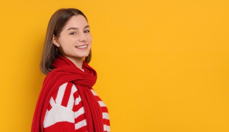 Photo of Beautiful woman in warm scarf on yellow background, space for text