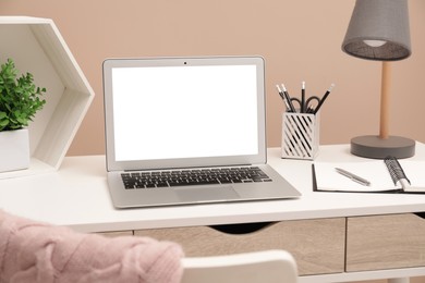 Comfortable workplace at home. Modern laptop with blank screen and stationery on wooden desk. Mockup for design